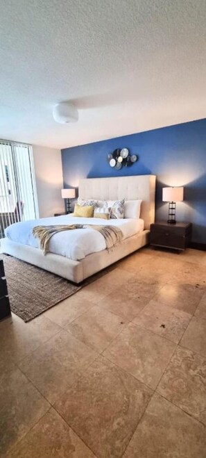 Relax in this serene bedroom with a large bed, bedside tables, and a decorative wall piece above.