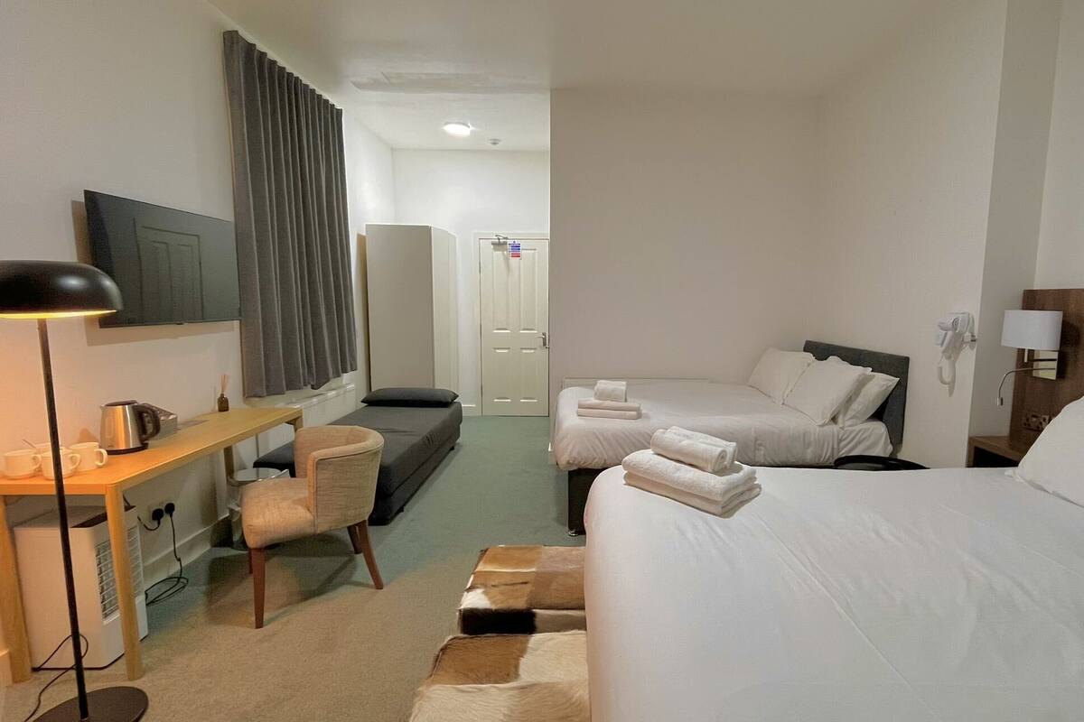 Hotellihuone, jossa on sänky, työpöytä, tuoli, televisio ja kylpyhuoneen ovi.