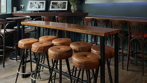 Angolo bar con tavoli di legno e sgabelli in pelle, una televisione che mostra 'OCTOBER sky sports' e un cartello con la scritta 'THE WELLINGTON HOTEL & PUB EST 1890'.