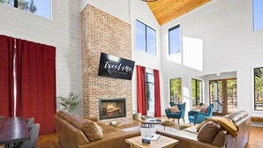 A spacious living area with a fireplace, red curtains, and a sign for TreeLine vacation rentals.