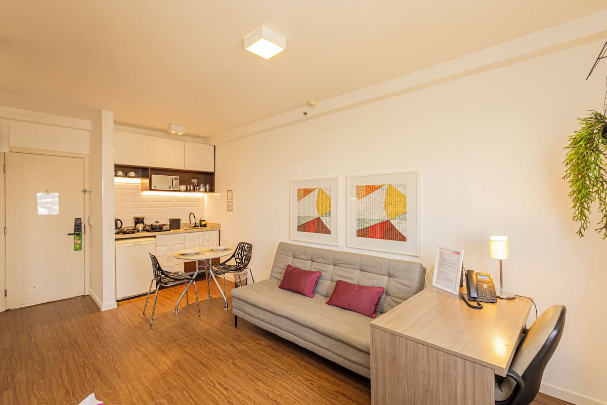 Un appartement moderne comprenant un coin cuisine, un canapé, un espace repas et un bureau avec une lampe.