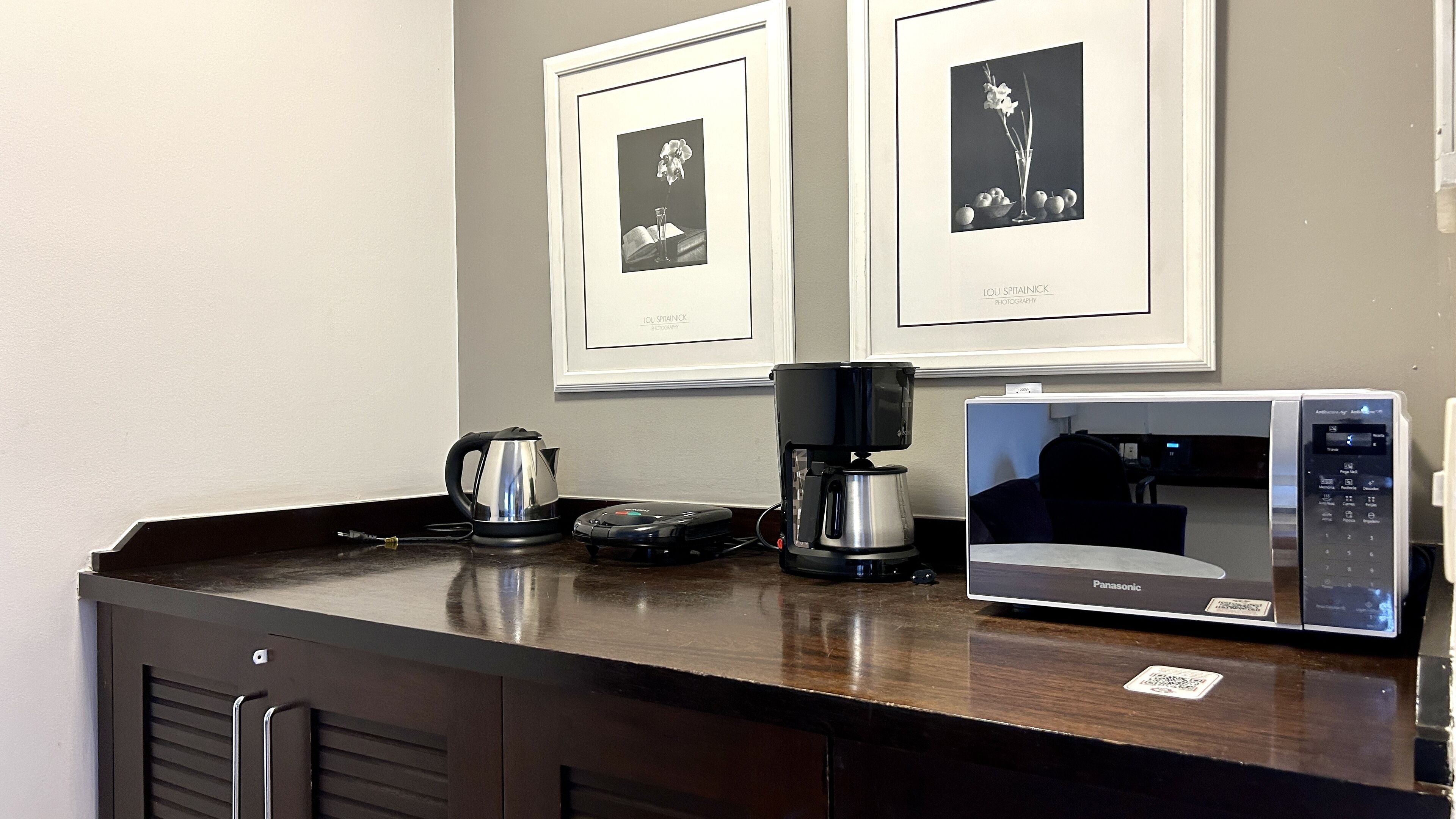 A kitchenette with a coffee maker, a microwave, and a kettle on a dark countertop.