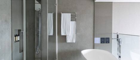 A modern bathroom with a glass-enclosed shower, a freestanding bathtub, and a towel rack with multiple towels.