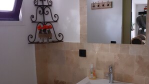 Une salle de bain avec un lavabo blanc, des toilettes et un élément décoratif en métal accroché au mur.