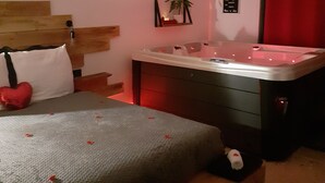 Une chambre à coucher avec un lit, une table de massage, un rideau rouge et une petite plante accrochée au mur.