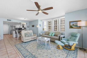 Un salon avec un ventilateur de plafond, un canapé, un fauteuil inclinable, une table basse et un tapis.