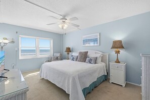Une chambre à coucher comprenant un lit, un ventilateur de plafond, une fenêtre avec vue, des lampes de chevet et une table de chevet.