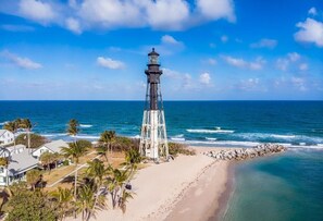A lighthouse on a beach with clear skies and calm sea.