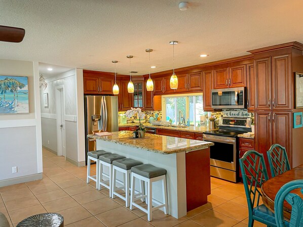 A modern kitchen with wooden cabinets, stainless steel appliances, and a central island with bar stools.
