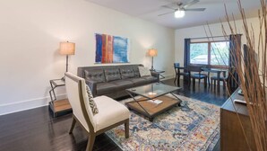 A modern living room with a leather sofa, a glass coffee table, and a dining area with a table and chairs.