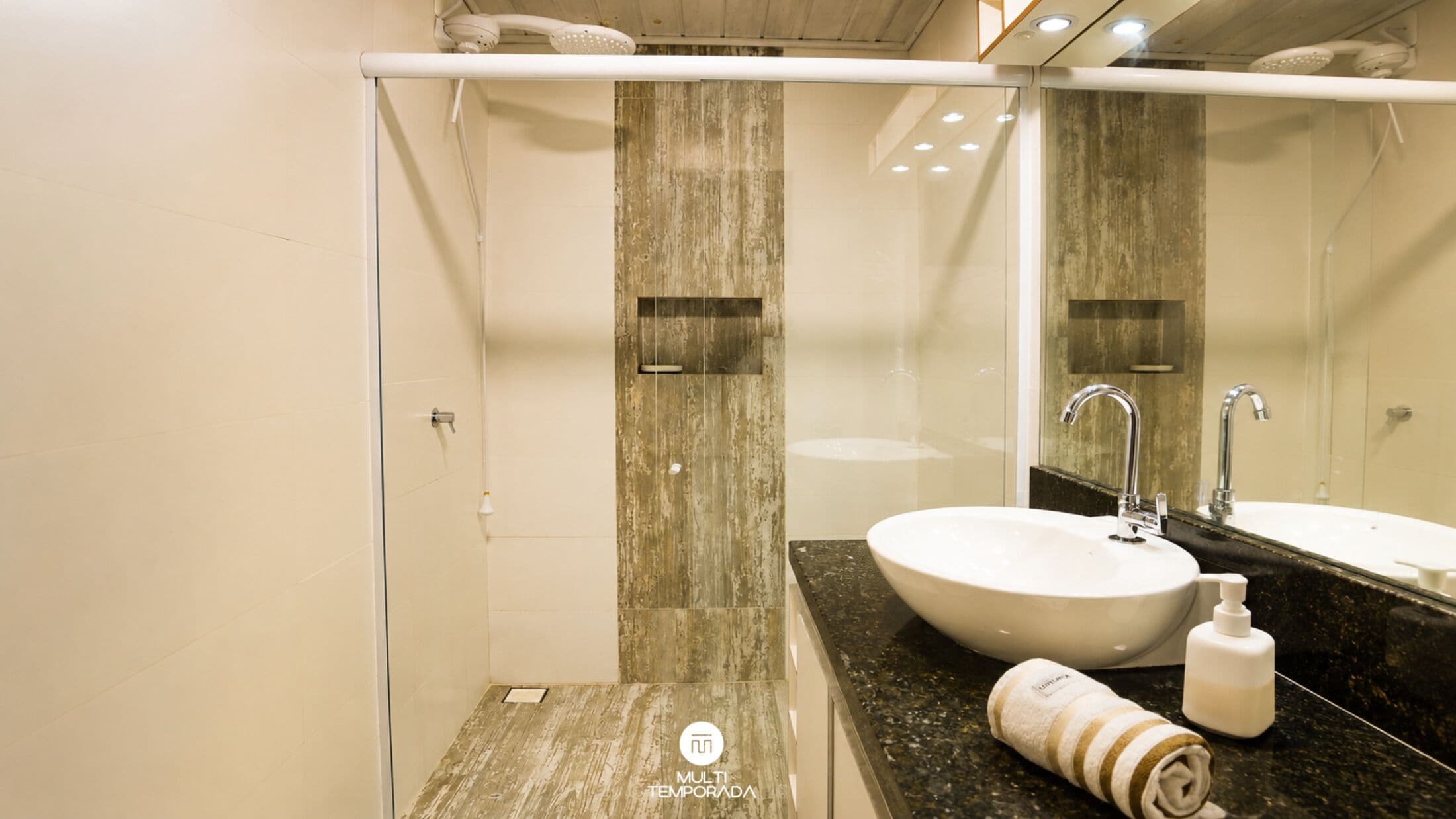 A modern bathroom with a glass shower enclosure, a white sink, and a large mirror.