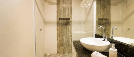 A modern bathroom with a glass shower enclosure, a white sink, and a large mirror.