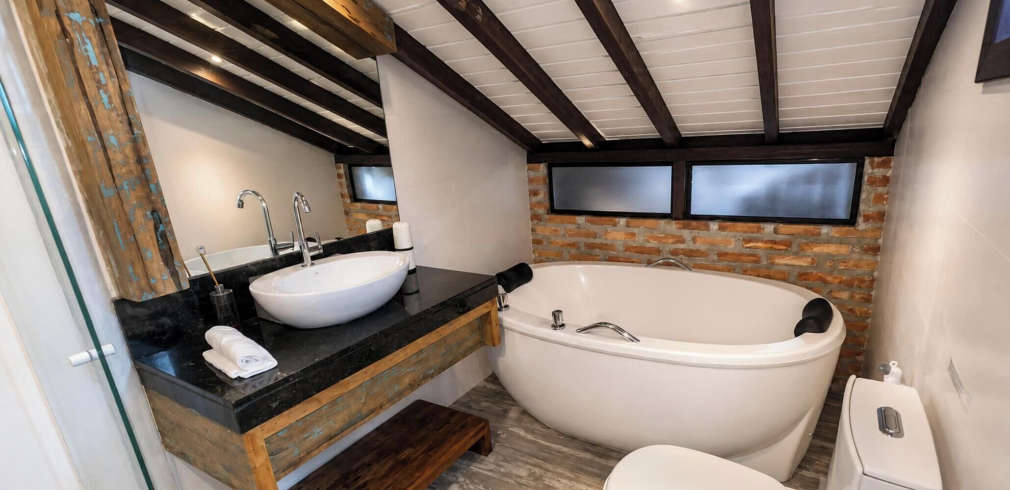 Un baño con una bañera grande, dos lavamanos y un tocador de madera.