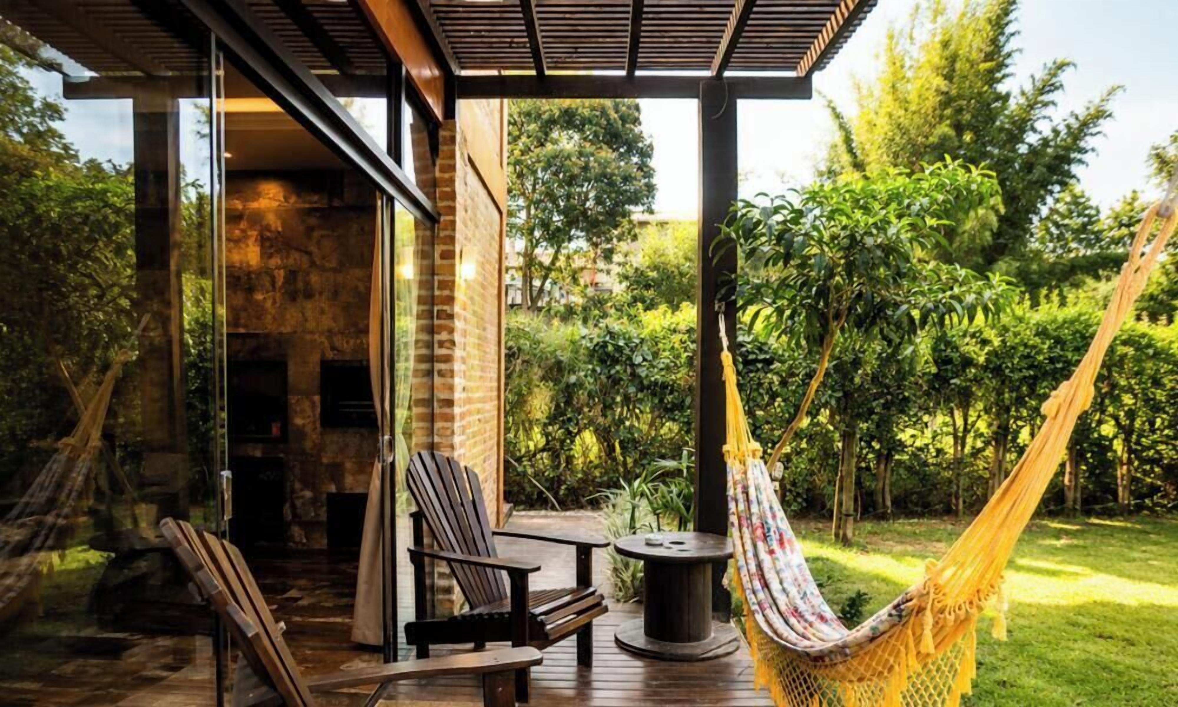 A wooden deck with outdoor furniture, a hammock, and a stone wall.