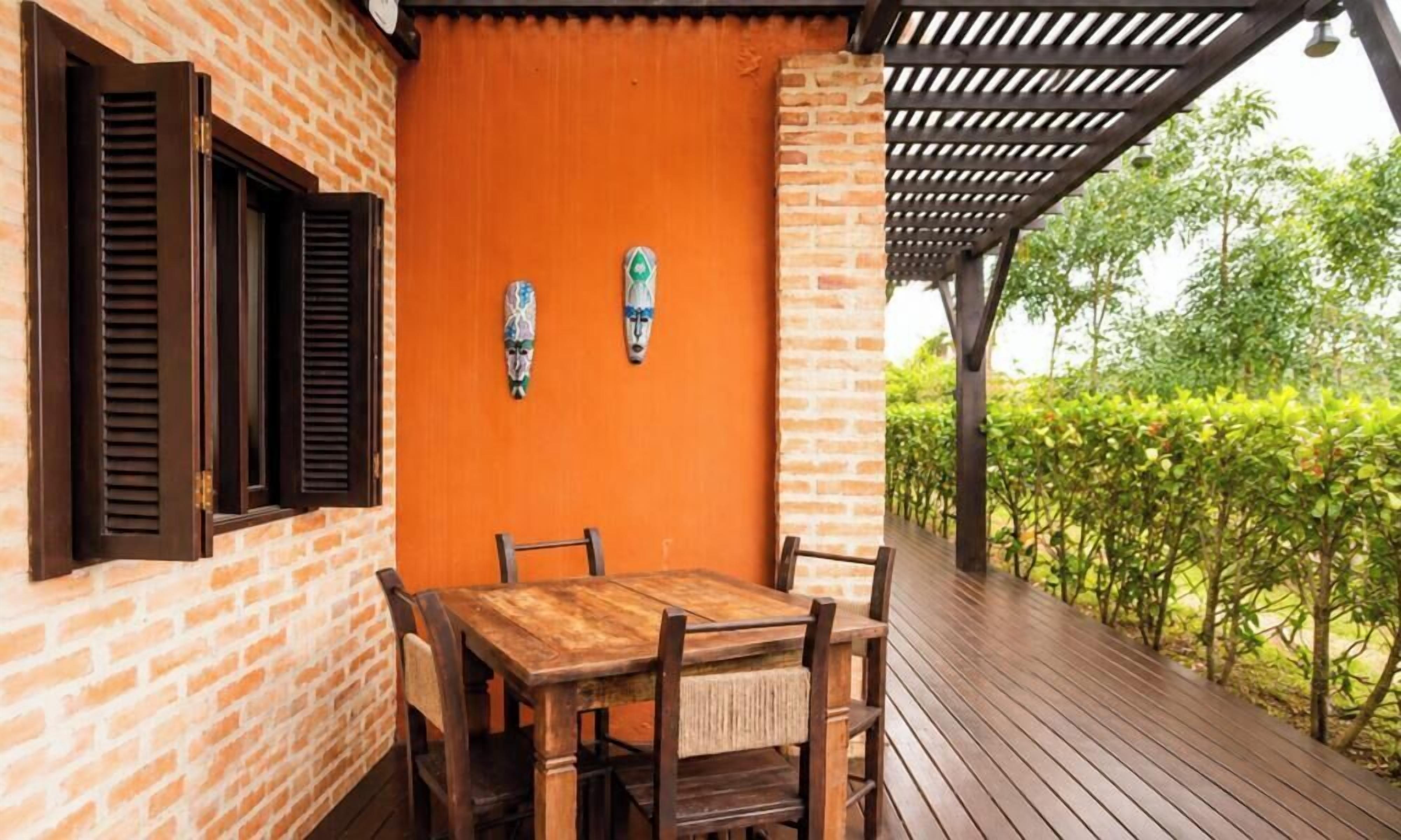 A wooden table with four chairs, a brick wall, and a wooden pergola.