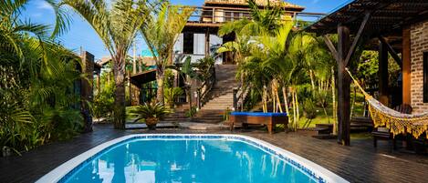 Una piscina al aire libre, sombrillas, sillones reclinables de piscina