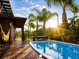 Una piscina al aire libre, sombrillas, sillones reclinables de piscina
