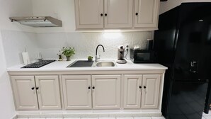 Eine Küche mit weißen Schränken, einem schwarzen Kühlschrank, einer Spüle und einer Kaffeemaschine.