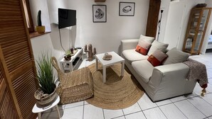 Ein Wohnzimmer mit Sofa, Couchtisch, Fernseher und Bücherregal.