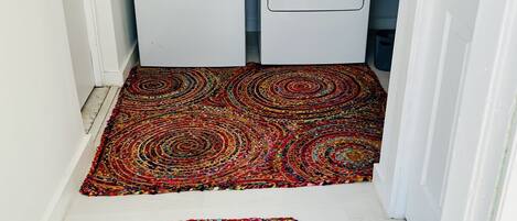 Un lavadero con dos lavadoras blancas y dos alfombras redondas de colores en el suelo.