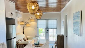A modern kitchen with a wooden ceiling, a central island with bar stools, a refrigerator, and pendant lighting. - Newly renovated cottage steps from the water (Bimini)