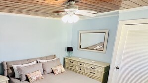 A bedroom with a bed, dresser, nightstands, a ceiling fan, and a door. - Newly renovated cottage steps from the water (Bimini)