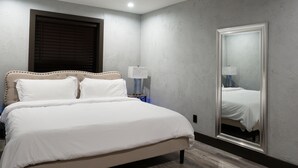 A bedroom with a large bed, a nightstand, a mirror, and a window with blinds. - The Reserve NEW condo, 2 blocks to Walla Walla Main Street (Walla Walla)