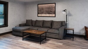 A living room with a gray sofa, a wooden coffee table, a floor lamp, and a framed cityscape picture on the wall. - The Reserve NEW condo, 2 blocks to Walla Walla Main Street (Walla Walla)