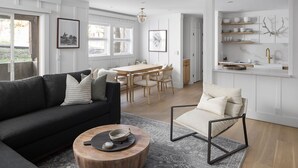 Ein modernes Wohnzimmer mit einer schwarzen Couch, einem Holztisch und einem Essbereich mit einem Holztisch und Stühlen.