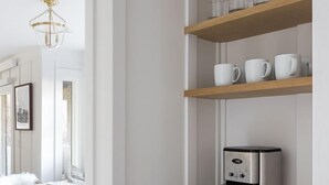 Eine moderne Küche mit Kaffeemaschine, Holzregalen und einem Essbereich mit Tisch und Stühlen.