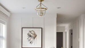 Ein Essbereich mit einem Holztisch, gestreiften Stühlen, einem weißen, flauschigen Teppich und einem gerahmten Kunstwerk an der Wand.
