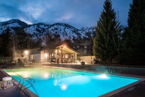 A swimming pool with a view of a mountain range at dusk.