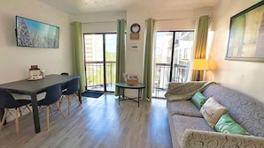 A living room with a dining table, sofa, and a view through a sliding door to an outdoor balcony. - Universal/Pool view +FREE parking. Newly renovated 2bdrm/2bth (Orlando)