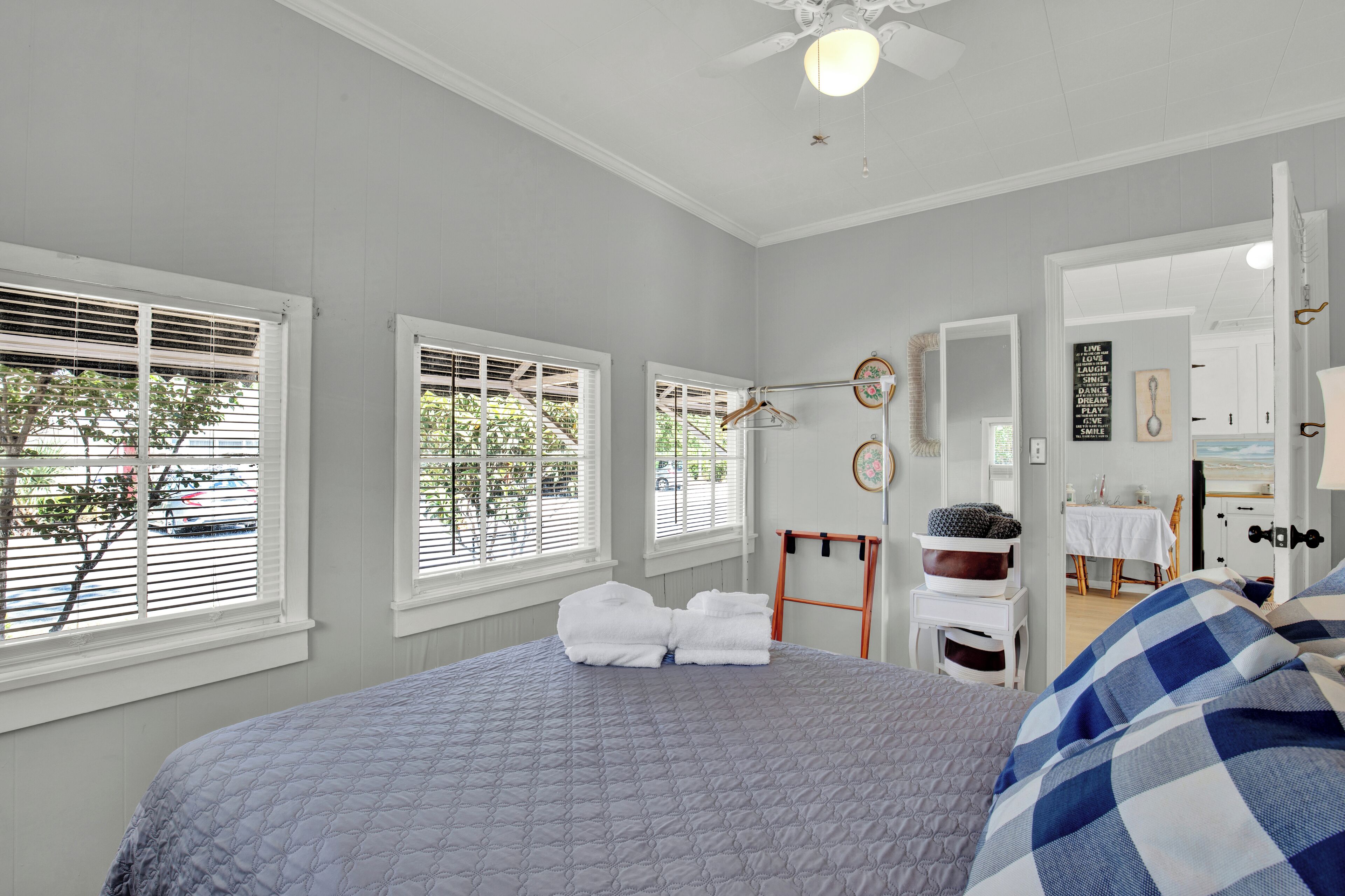 A bedroom with a bed, a window, a ceiling fan, and a door leading to a bathroom.