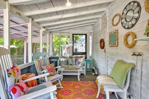 A cozy porch with white furniture, a colorful rug, and decorative items. - Charming Tybee Cottage, great location! (Tybee Island)