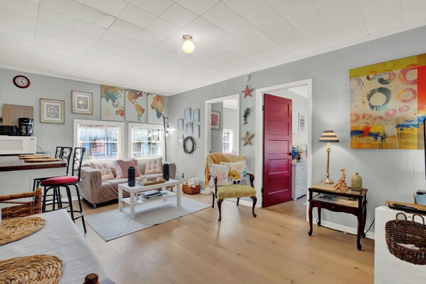 A spacious living room with a sofa, armchairs, a coffee table, and a dining area with a table and chairs. - Charming Tybee Cottage, great location! (Tybee Island)