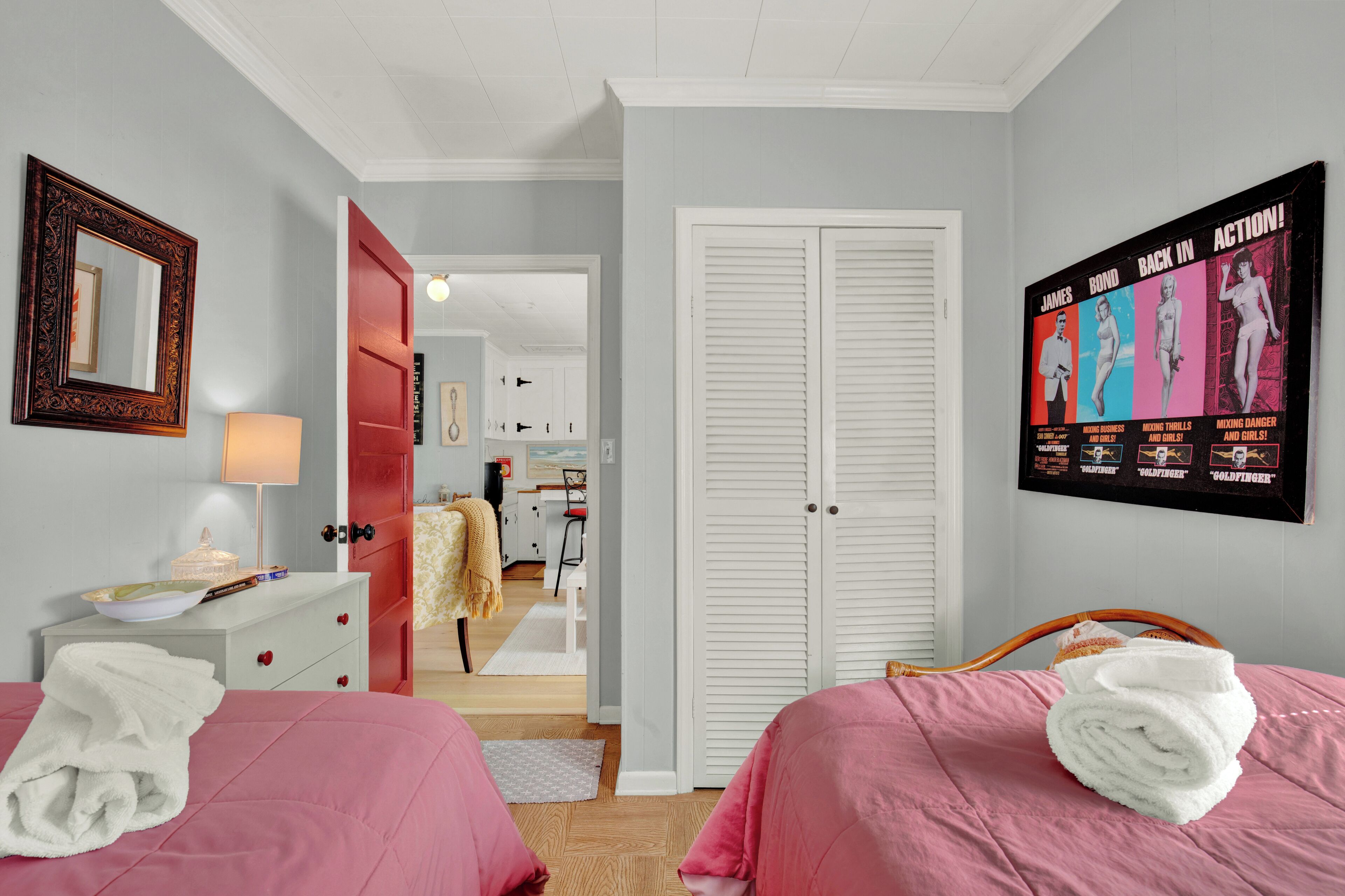 Ein Schlafzimmer mit zwei Betten, einem Kleiderschrank, einem Spiegel und einem Poster an der Wand.