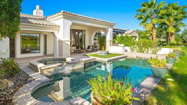 Una casa moderna con piscina, mobiliario de patio y exuberante jardinería.