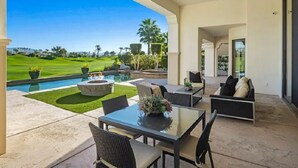 Un patio con piscina, mobiliario exterior y vista a un campo de golf.