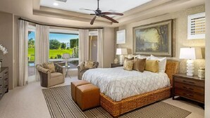 Un dormitorio amplio con una cama grande, ventilador de techo, vistas al exterior y un comedor con mesa y sillas.