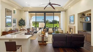 Amplia sala de estar con un ventanal grande, ventilador de techo, chimenea y televisor.