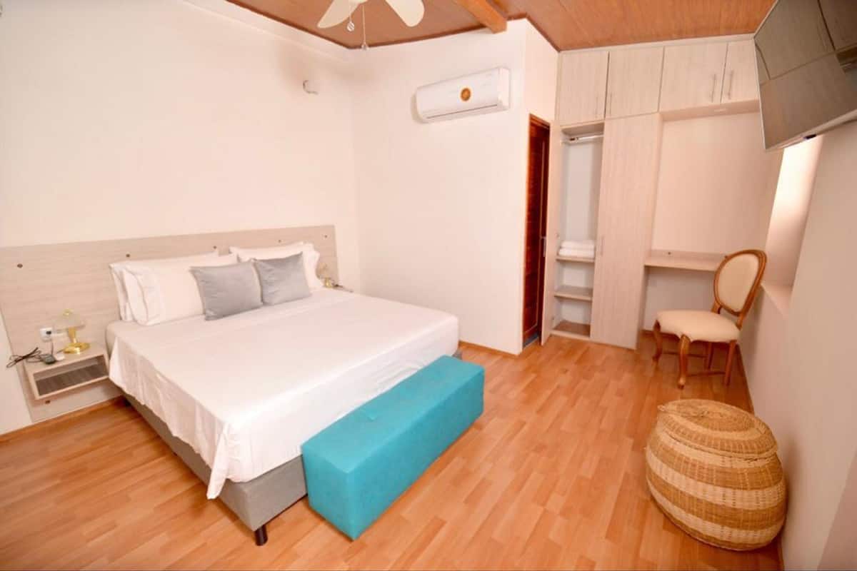 A bedroom with a bed, a bedside table, a chair, a wardrobe, and a television.