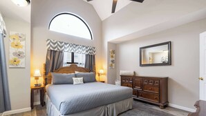 Een slaapkamer met een bed, nachtkastjes, een dressoir en een grote spiegel.