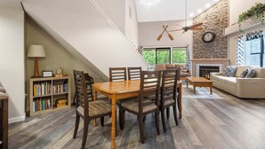 Een eetgedeelte met een houten tafel en stoelen, een boekenkast en een open haard.