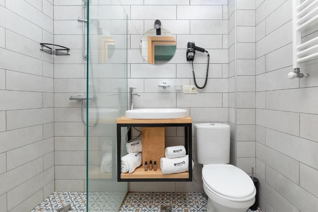 A modern bathroom with a glass shower enclosure, a wooden vanity with a sink, a toilet, and a towel rack.