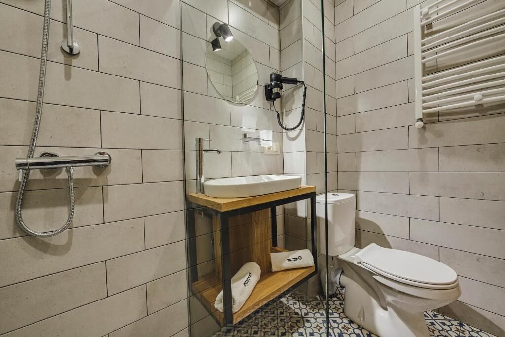 A modern bathroom with a glass shower enclosure, a white sink, and a toilet.