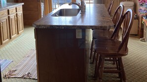 A kitchen with a large island, wooden cabinets, and a hanging light fixture. - Slice of Heaven - Private pool - 4 Bedroom (Colo)