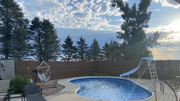 An outdoor swimming pool with a slide, surrounded by a wooden fence and trees. - Slice of Heaven - Private pool - 4 Bedroom (Colo)