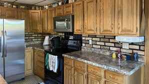 A kitchen with wooden cabinets, a stainless steel refrigerator, a microwave, a stove, and a coffee maker. - Slice of Heaven - Private pool - 4 Bedroom (Colo)