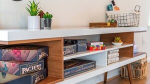 A white shelf with chess sets and a small plant.